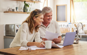 senior man and wife looking over paperwork and computer